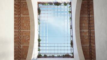 A courtyard with a grid-like window structure, brick walls, and arches.