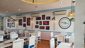 A restaurant interior with white tables and chairs, air conditioning units, and framed artwork on the walls. - Hotel Punto Poza Rica (Poza Rica)