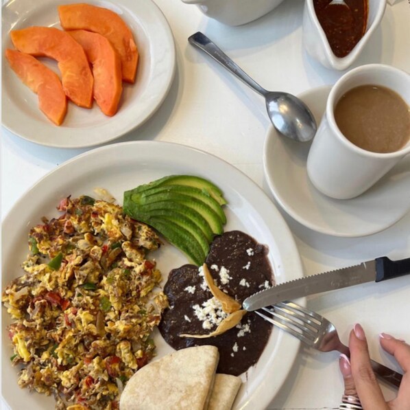 Un plato con huevos revueltos, frijoles refritos y aguacate en rodajas.