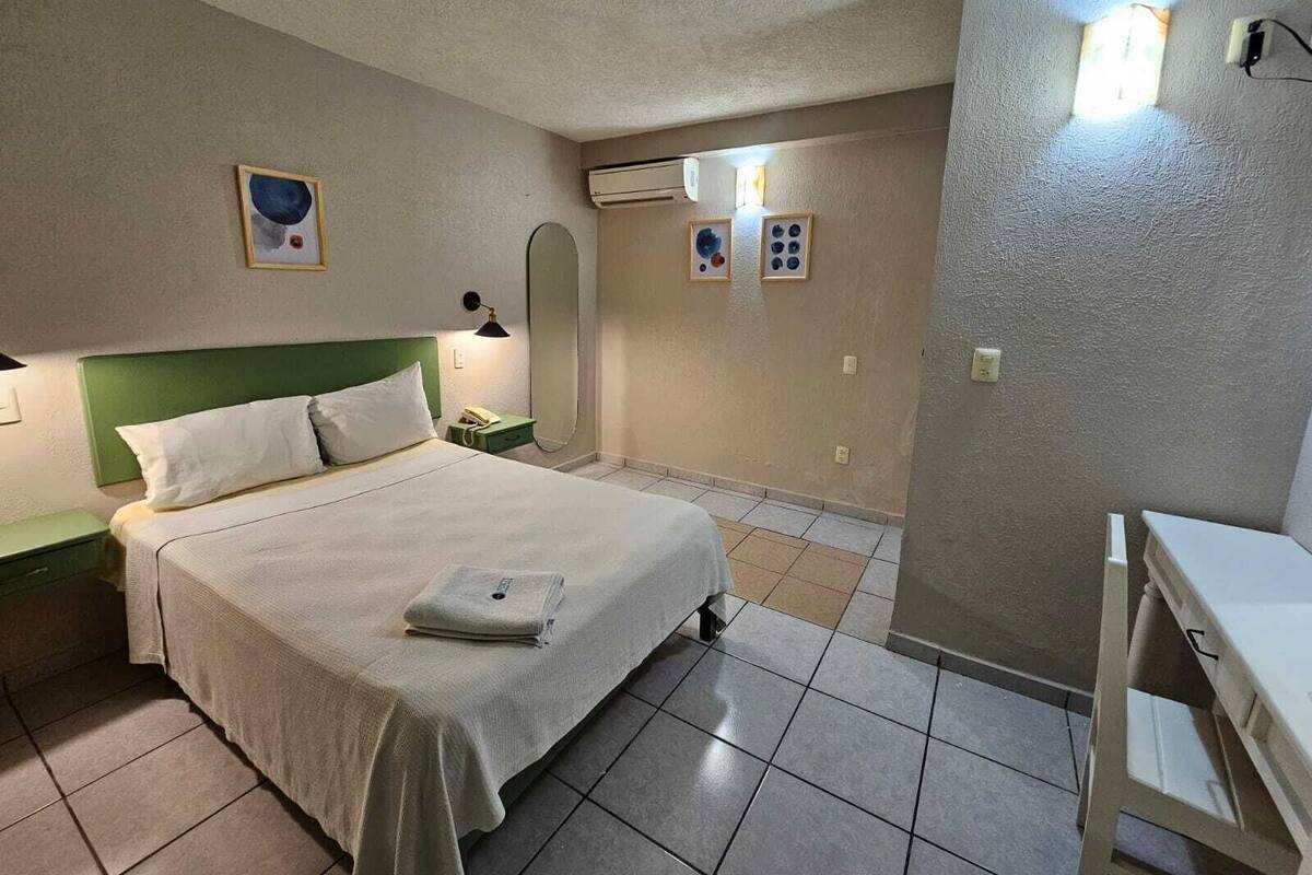 A bedroom with a bed, a nightstand, a desk, and a chair.
