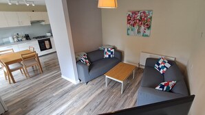 A modern living area with a sofa, a coffee table, and a dining table with chairs. - Fisherman's Lodge | Lough Corrib | 3 Bed | Galway Lakeside | Lake Access (County)