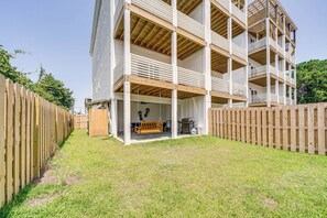 Een meerhoog gebouw met een overdekt terras en een houten omheining.