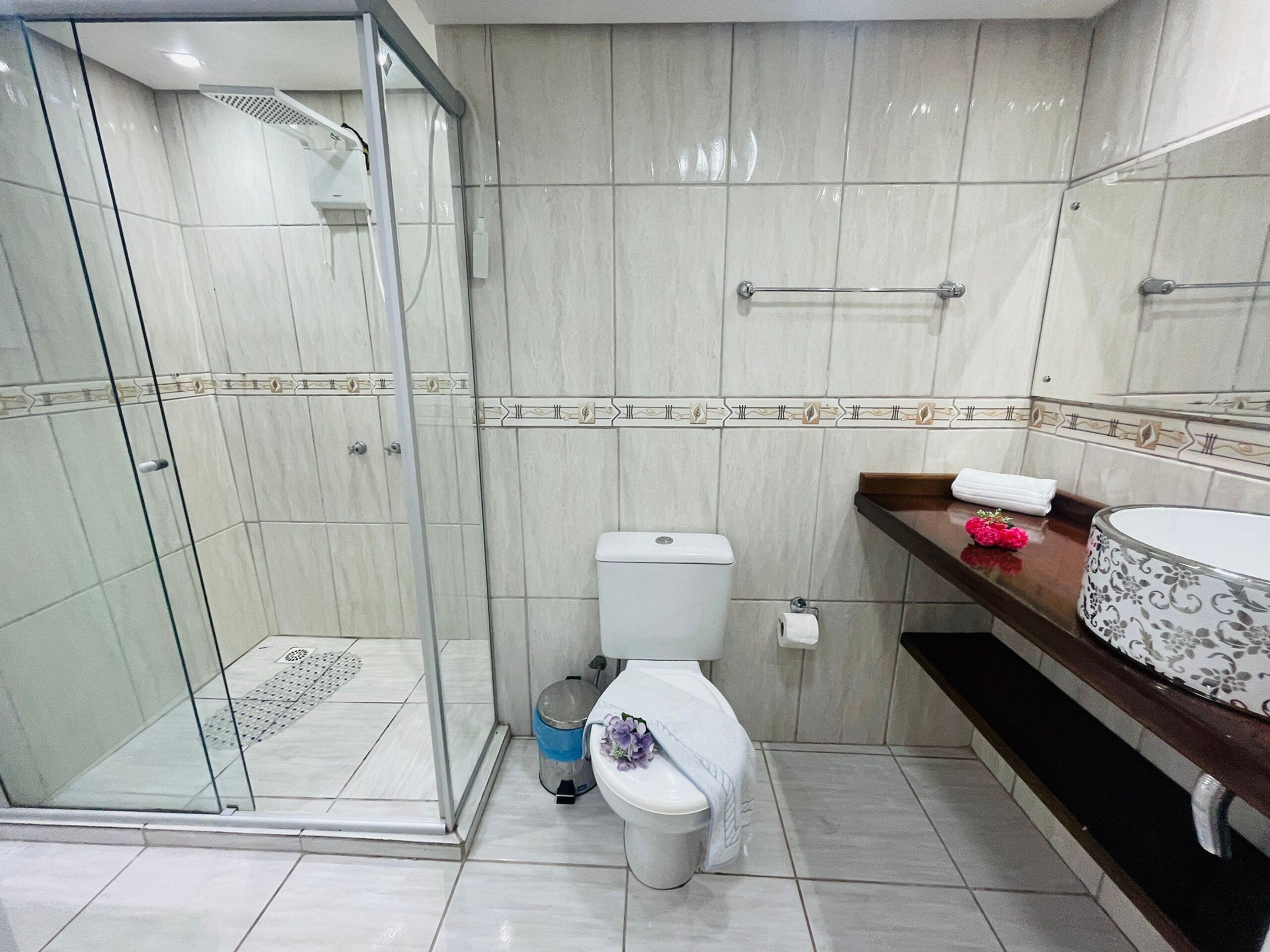 Une salle de bain avec une douche à parois de verre, des toilettes et un lavabo avec un miroir.