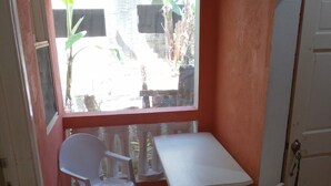 A small room with a white table and four white chairs, a window with a view of the outside, and a door to the right.