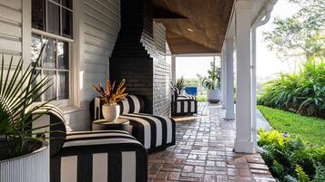 A covered outdoor seating area with black and white striped sofas and planters.