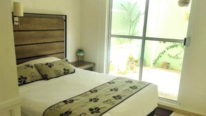 A bedroom with a bed, a nightstand, a window, and an air conditioning unit. - 13 minutes away from quinta avenida (Q.R.)