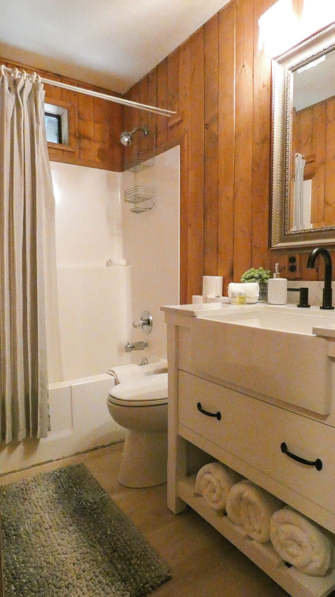 Un baño con detalles de madera, un lavamanos blanco, un espejo y una ducha.
