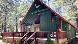 A cabin with a wooden deck, a staircase, and a small tree in front. - Bellwood Cabin (Forest Lakes Estates)
