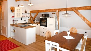 Una cucina accogliente con travi in legno, mobili bianchi e un'isola centrale.