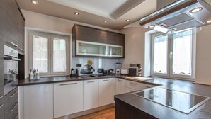 A modern kitchen with a central island, white cabinetry, and a built-in oven. - Lovely apartment in Smarje (Smarje)