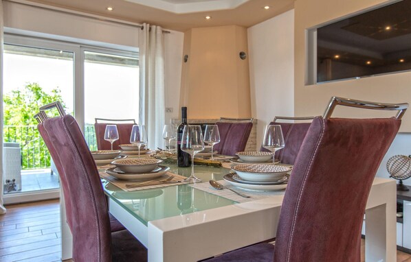 A dining area with a glass table, red upholstered chairs, and a view of greenery outside. - Lovely apartment in Smarje (Smarje)