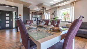 A modern dining area with a glass table, dark chairs, and a view of the kitchen and living room. - Lovely apartment in Smarje (Smarje)
