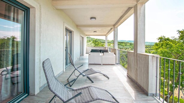 A balcony with two lounge chairs, a small table, and a view of greenery. - Lovely apartment in Smarje (Smarje)