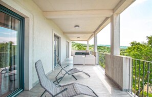 A balcony with two lounge chairs, a small table, and a view of greenery. - Lovely apartment in Smarje (Smarje)