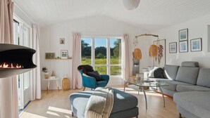Tilava olohuone, jossa on takka, sininen nojatuoli, harmaa sohva ja lasinen sohvapöytä.