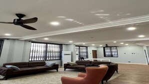 A spacious living room with a brown sofa, a red armchair, and a ceiling fan.