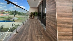 A balcony with a view of a residential area, a potted plant, and a glass railing.