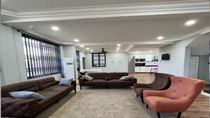 A spacious living room with a brown sofa, a brown sectional, and a brown armchair.