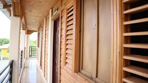 A wooden corridor with a tiled floor, wooden shutters, and a metal railing. - Increíbles junior suites 1BR (Coconuts 1) (Punta Cana)