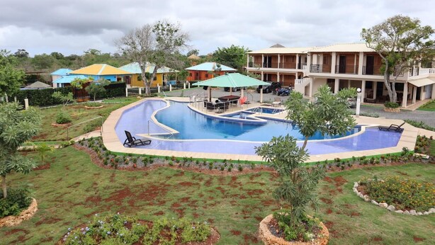 A swimming pool with lounge chairs, surrounded by landscaped gardens and a building with multiple balconies. - Increíbles junior suites 1BR (Coconuts 1) (Punta Cana)