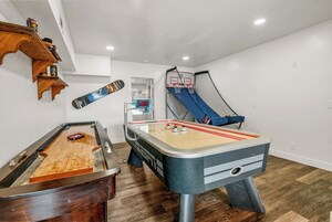 Una habitación con mesa de fútbol, mesa de ping pong y aro de baloncesto.