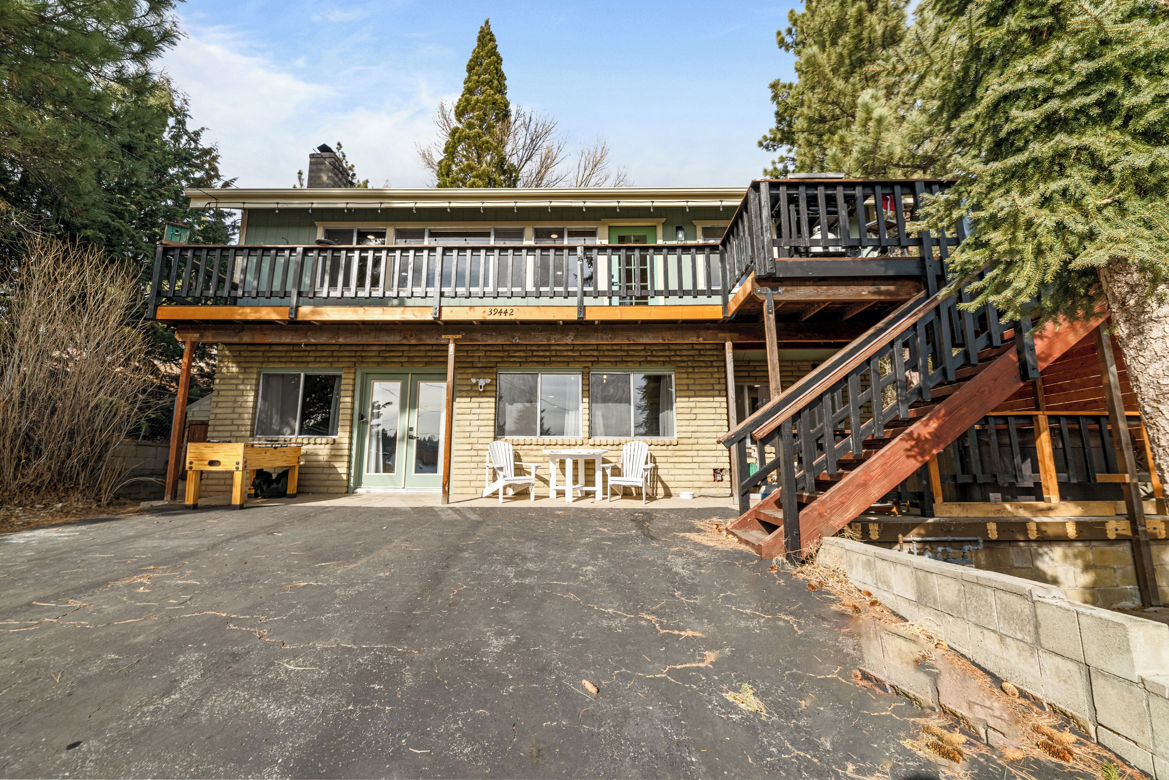 A two-story building with a balcony, outdoor seating area, and a staircase leading to an upper level.