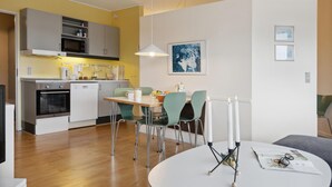 Une cuisine moderne avec un coin repas, comprenant une table en bois, des chaises et un luminaire suspendu.