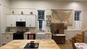 Una cocina con armarios blancos, una isla de madera, una estufa y un mapa grande en la pared.