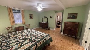 A bedroom with a large bed, a dresser, a mirror, and a ceiling fan.