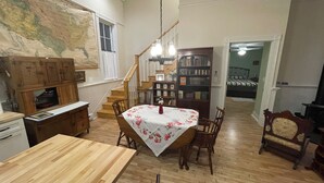 Un comedor con una mesa de madera, sillas, un mapa en la pared, una escalera y una estantería.