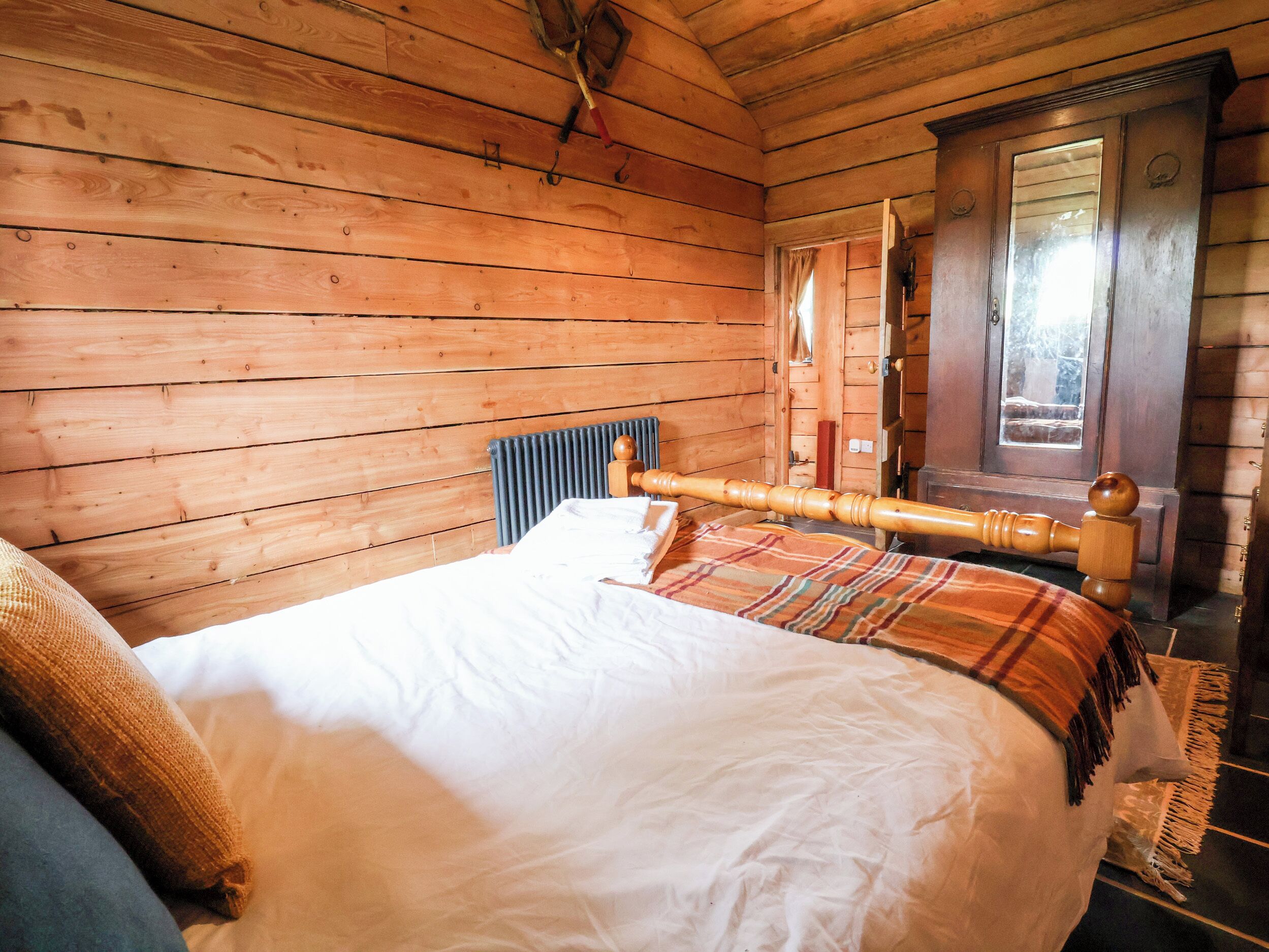 Een houten kamer met een bed, een raam en een deur.