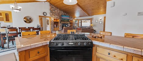 Una cocina con estufa central, armarios de madera y pared de piedra.