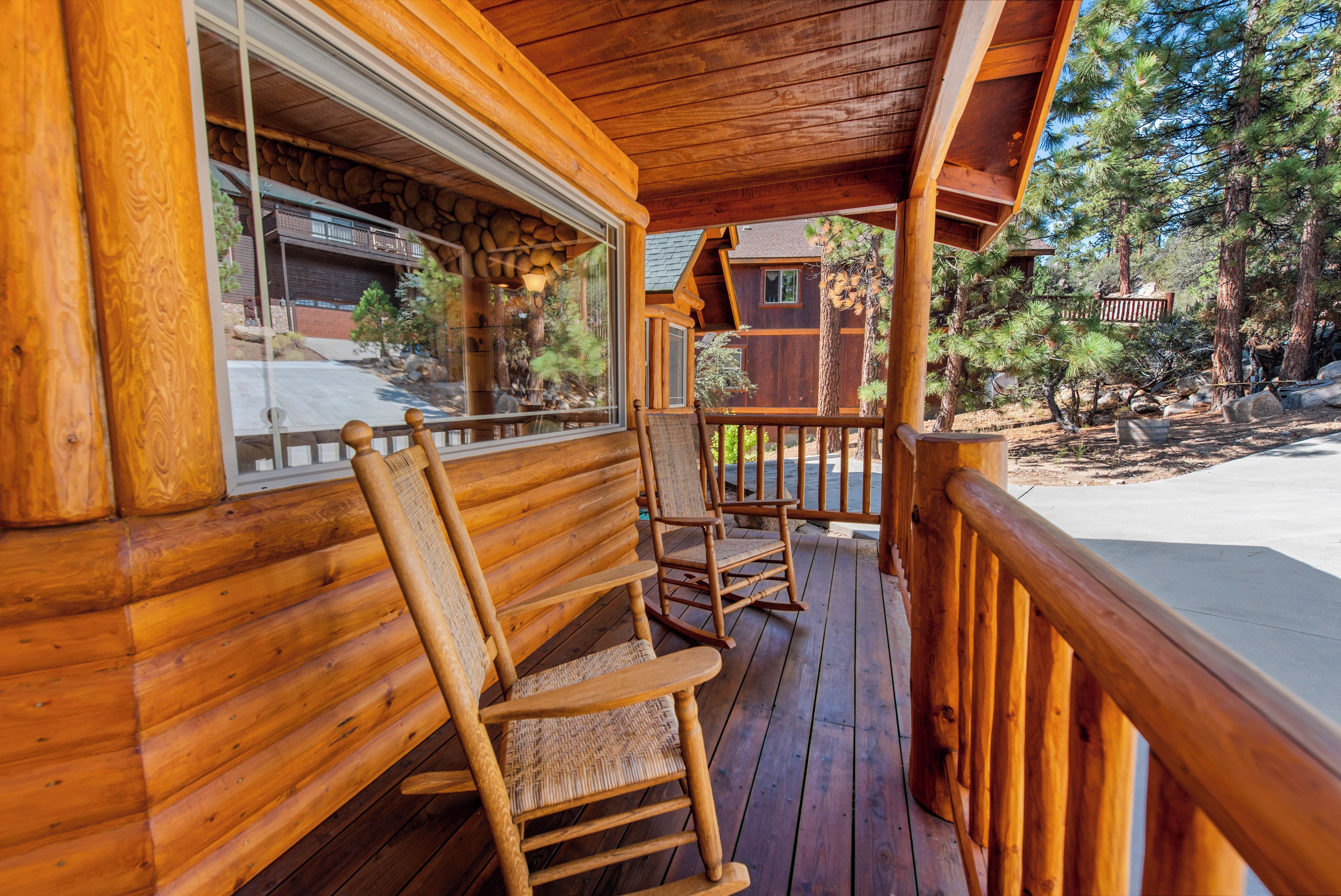 Eine Holzhütte mit Veranda, Schaukelstühlen und einem durch das Fenster sichtbaren Steinmauerwerk.