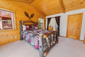 A wooden cabin bedroom with a bed, a window, a door, and a ceiling. - Kubo Del Sol (Big Bear Lake)