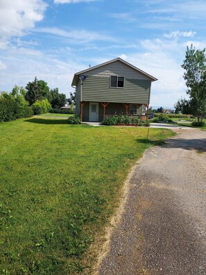 A two-story house with a front porch, a driveway, and a well-maintained lawn.