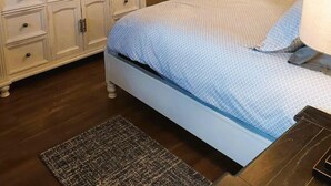 Un dormitorio con cama, cómoda, espejo, ventana y ventilador de techo.