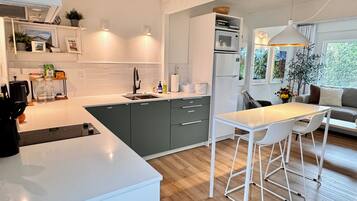 Een moderne keuken met een centraal eiland, een eethoek met barkrukken, en uitzicht op het omliggende landschap.