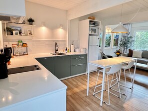A modern kitchen with a central island, a dining area with bar stools, and a view of the outdoors. - Private Wellness Retreat • Heated Saltwater Pool • Gym • A/C • Views (San Rafael)