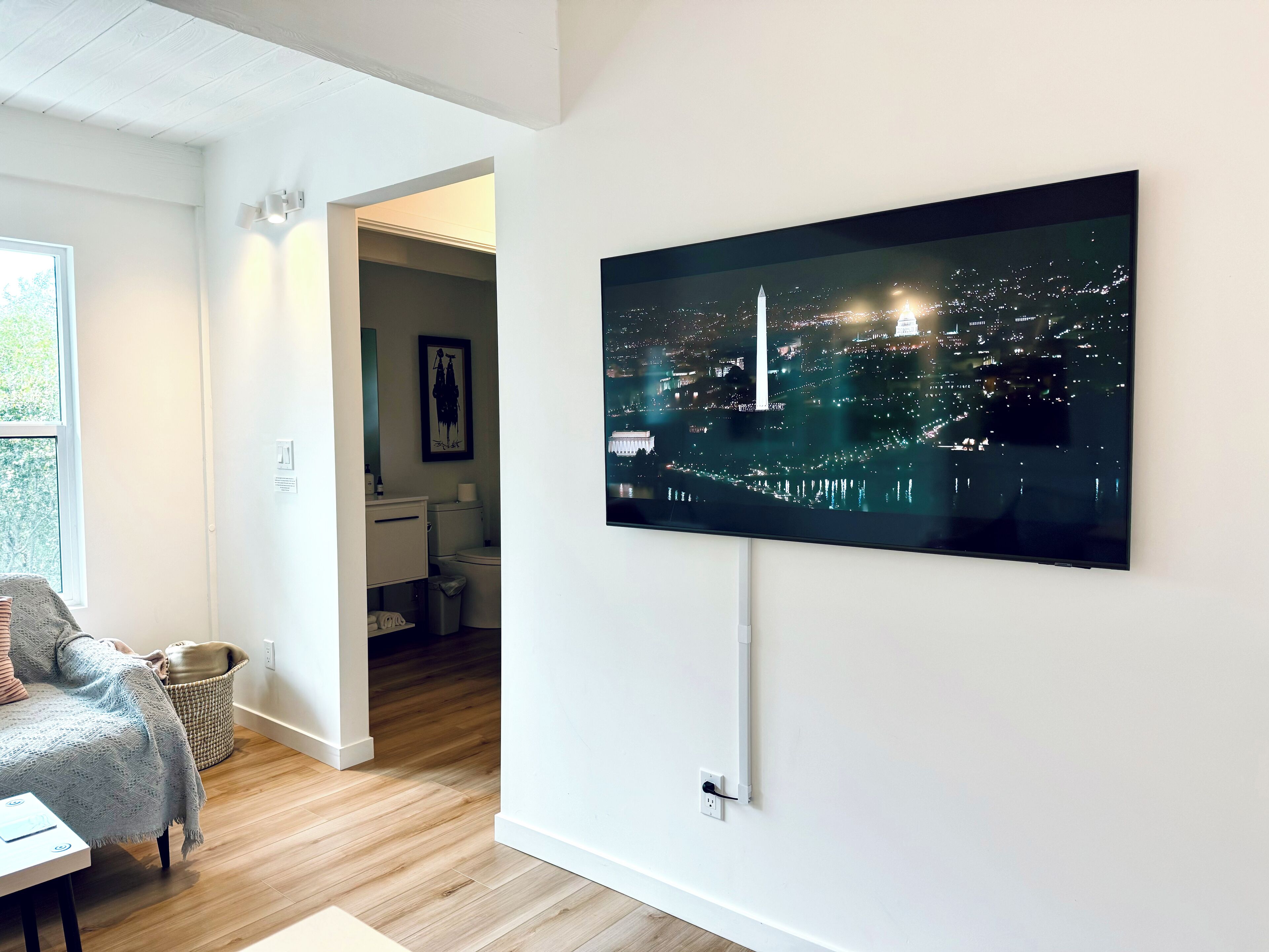 A modern living room with a large flat-screen TV mounted on the wall displaying a cityscape at night.