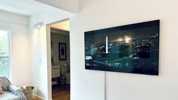 A modern living room with a large flat-screen TV mounted on the wall displaying a cityscape at night.