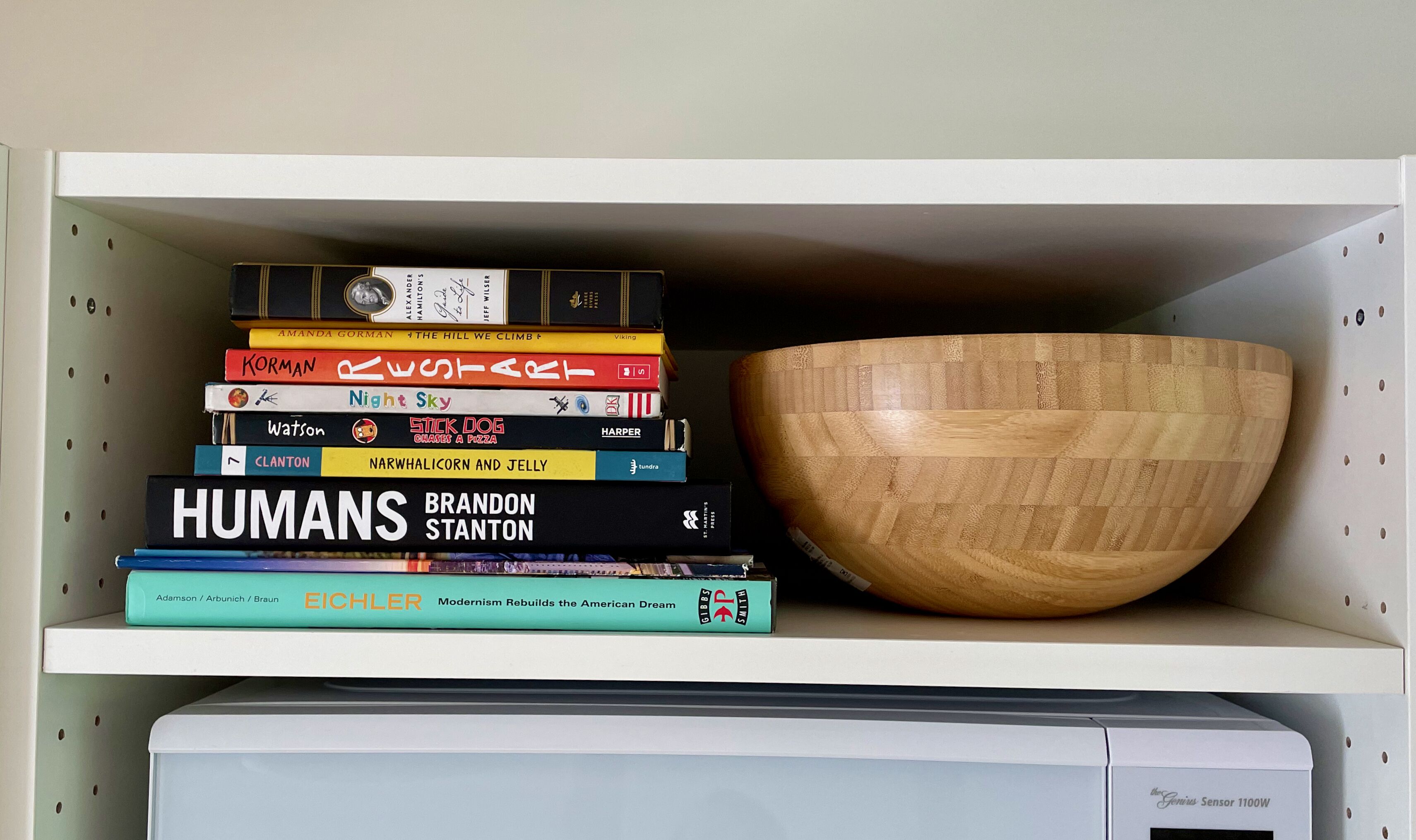 A shelf with a stack of books and a wooden bowl.