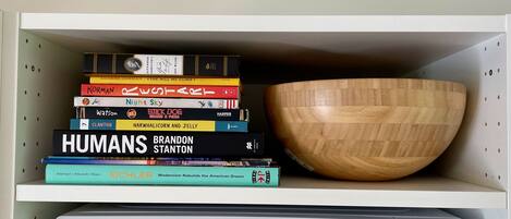A shelf with a stack of books and a wooden bowl.