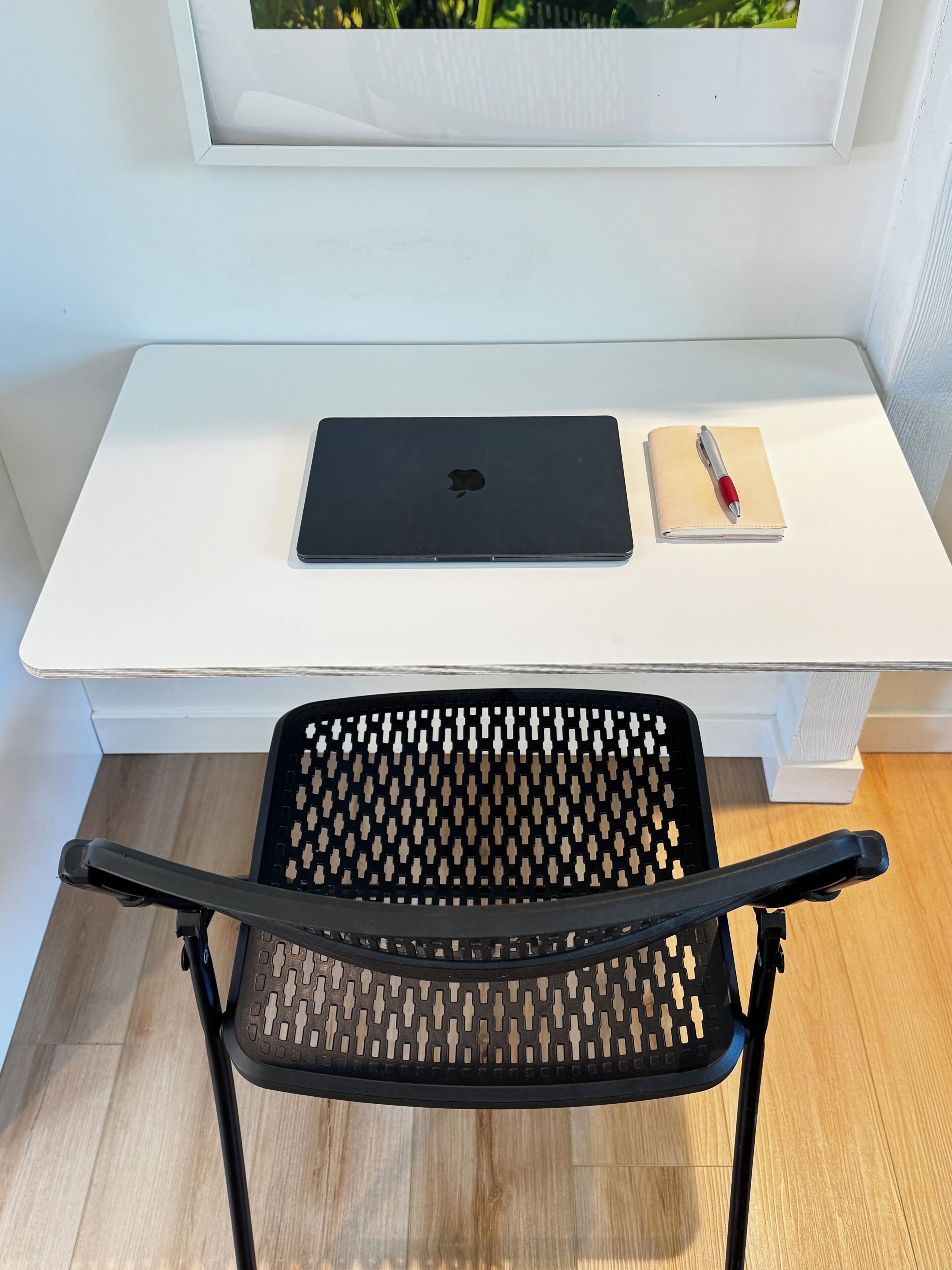 A white desk with a laptop and a notebook.