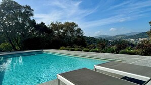 A swimming pool with clear blue water, surrounded by greenery and overlooking a scenic landscape. - Private Wellness Retreat • Heated Saltwater Pool • Gym • A/C • Views (San Rafael)