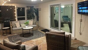 Ein gemütliches Wohnzimmer mit einer Couch, zwei Sesseln, einem Couchtisch und einem an der Wand montierten Fernseher.