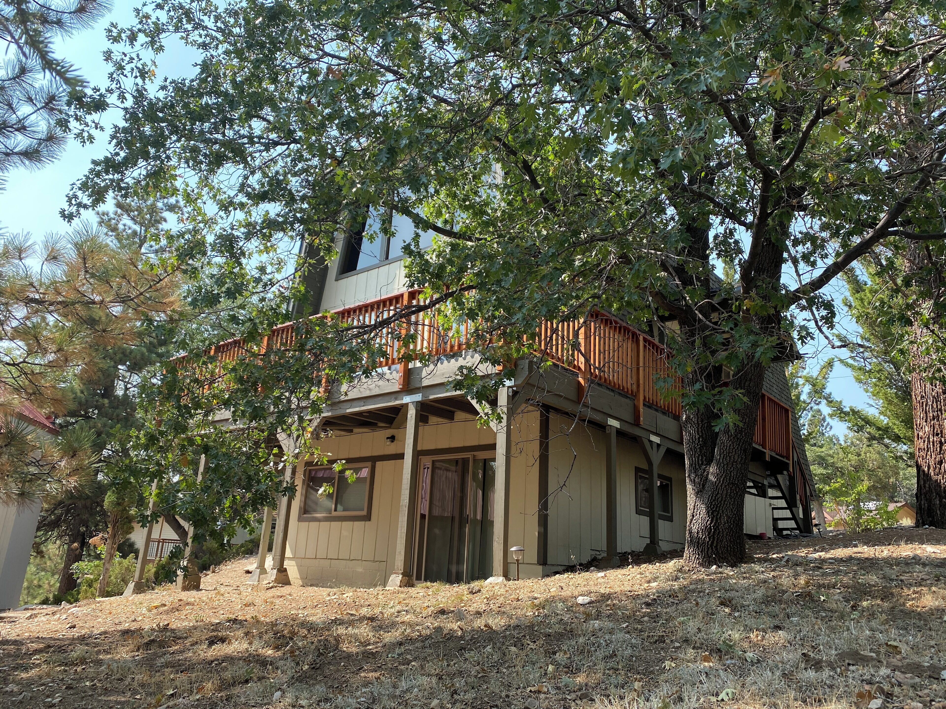 A two-story house with a wooden deck and a staircase leading to the upper level.