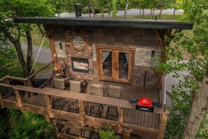 Une terrasse en bois avec des meubles dâextĂ©rieur, une cheminĂ©e en pierre et une vue sur la verdure environnante.