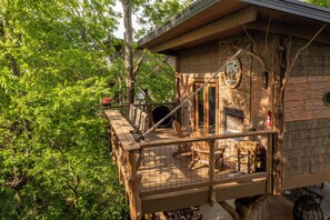 A treehouse with a wooden deck, a rope ladder, and a small enclosed area with a fire extinguisher.