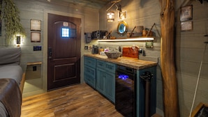 A compact kitchen with wooden cabinets, a built-in oven, and a hanging light fixture. - Family Adventure Treehouse | 20-ft Slide + Secret Beds | Sleeps 6 | Smoky Mtns (Sevierville)