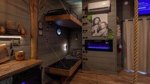 Una habitación acogedora con una cama litera, chimenea, televisor y pared de madera.